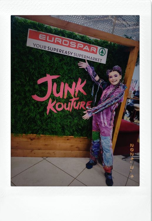 Student in creative costume poses beside Junk Kouture and Eurospar display sign