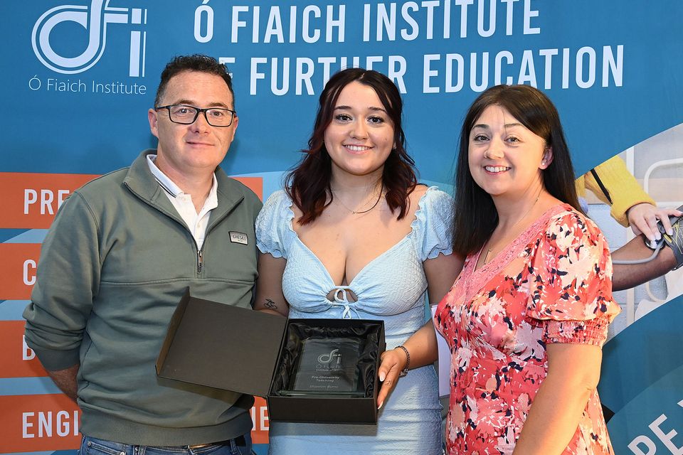 Graduate Shannon Byrne celebrates with her family, holding her OFI award at the ceremony.